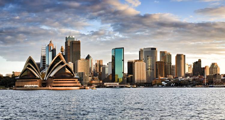 Iconisch operagebouw met stadsskyline op de achtergrond.