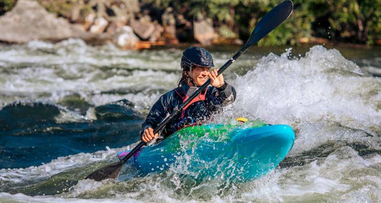 Personne faisant du kayak à travers des rapides d'eau vive turbulents.