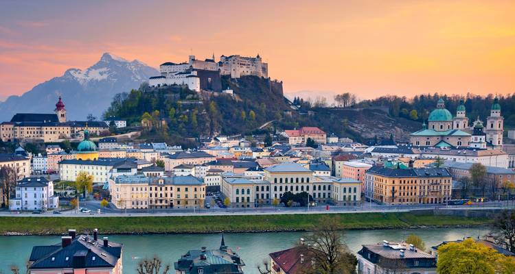 Aerial view of Salzburg, Austria with Hohensalzburg Fortress and surrounding buildings at sunset.