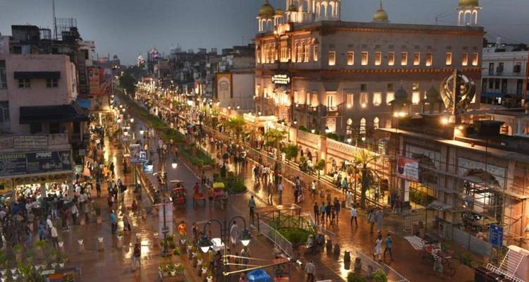 Rue animée avec des lumières et des gens devant un bâtiment historique.