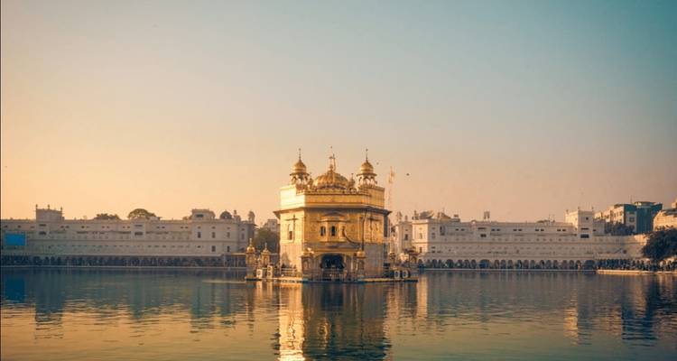 Temple doré entouré d'eau au coucher du soleil.