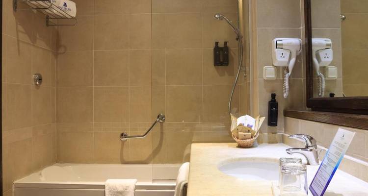 Hotelbadkamer met beige tegels en badkuip.