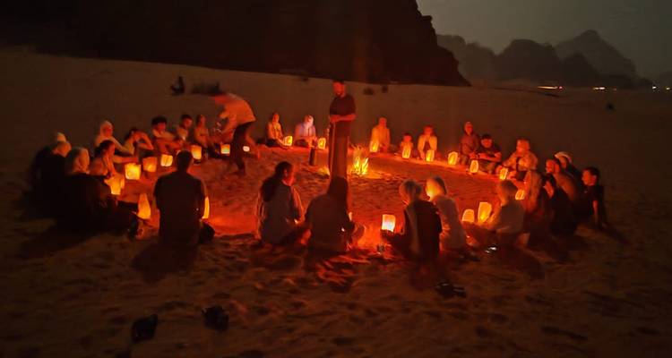 Groep zittend in een cirkel met lantaarns in een woestijn.