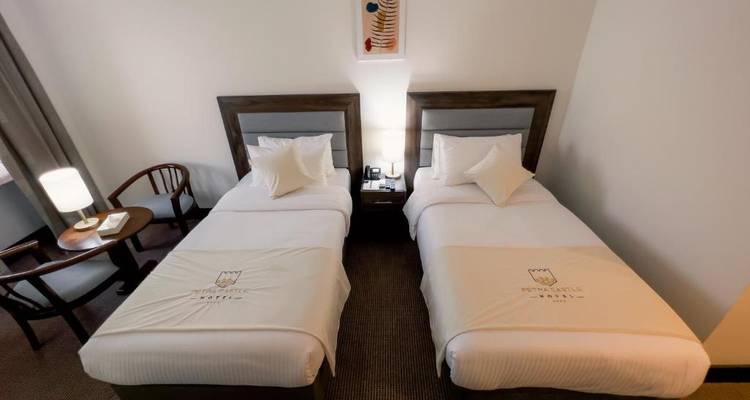 Twee eenpersoonsbedden in een hotelkamer, moderne en schone inrichting.