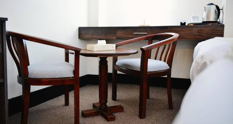 Kleine houten tafel met twee stoelen in een hotelkamer.