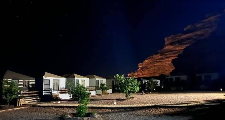 Nachtbeeld van woestijnkamp hutten en rotsformaties.