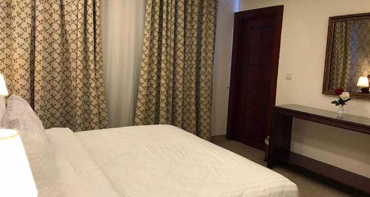 Hotelkamer met tweepersoonsbed en gordijnen met motief.