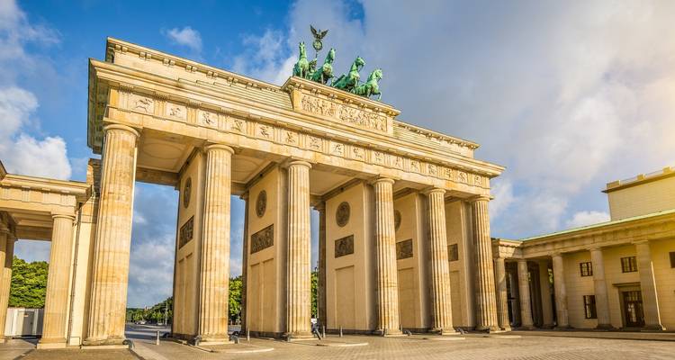 Porte historique sur une place de ville sous un ciel bleu.