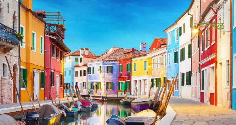 Bunte Gebäude säumen einen Kanal mit Booten in Venedig.