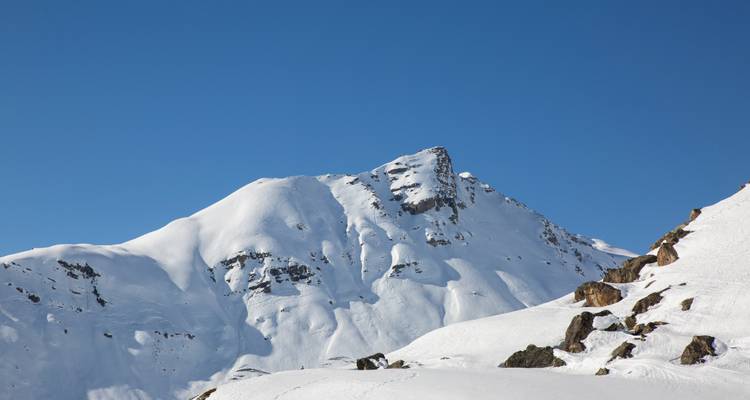 Scherpe sneeuwbedekte top die tegen een wolkenloze diepblauwe lucht uitsteekt.