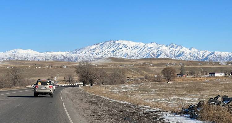 Open road leading to snow-capped mountains in the background.