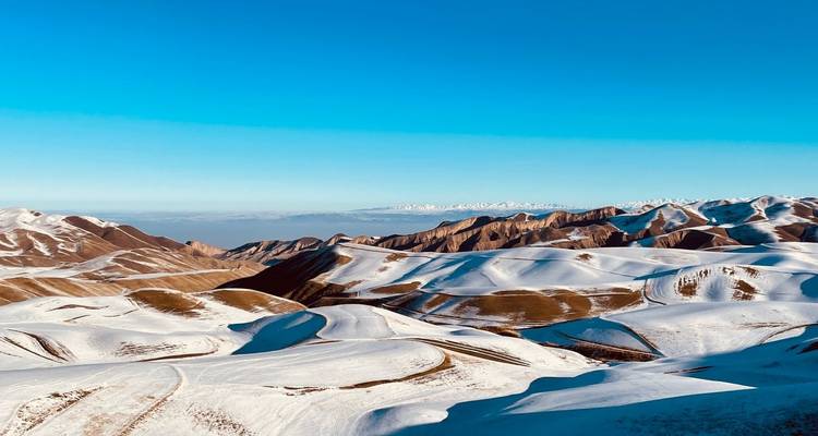 Vast snowy mountain landscape under a clear blue sky.