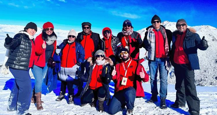 Group of people in winter clothing posing in a snowy mountain landscape.