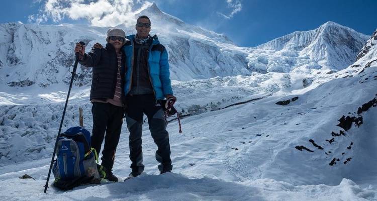 Randonneurs posant devant une montagne enneigée.