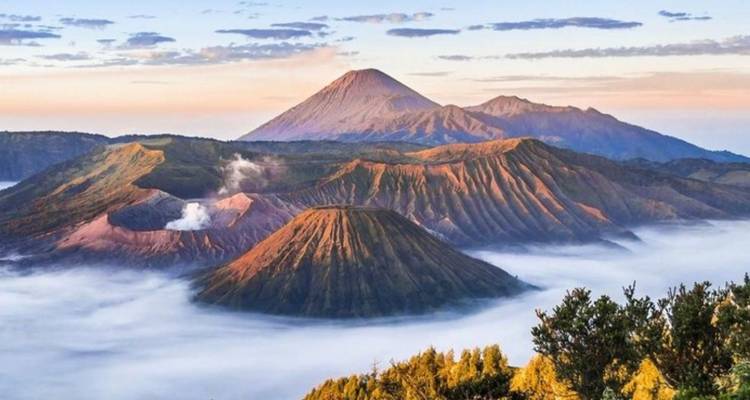 Sunrise over Mount Bromo’s stratovolcanoes with flowing mist and pastel skies.
