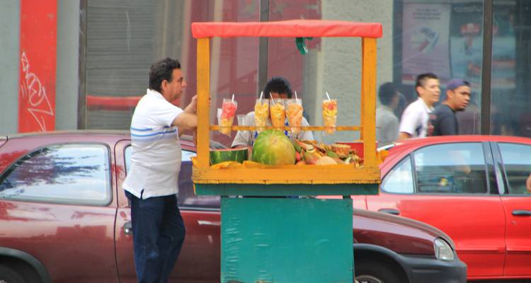 Straatverkoper die verse vruchtensappen verkoopt vanuit een kleurrijke kar.
