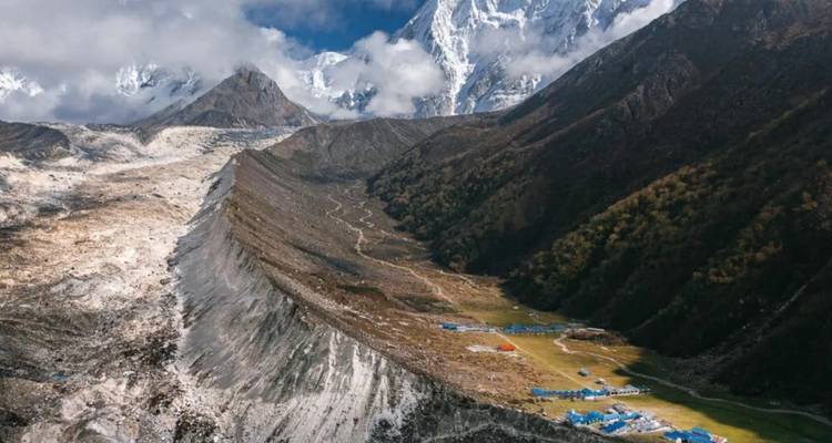 Weites Tal mit blauen Dächern und schneebedeckten Bergen in der Ferne.