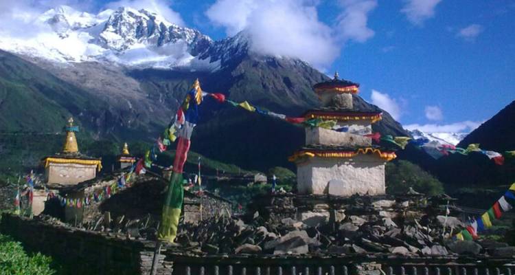 Chorten mit Gebetsfahnen vor einer Kulisse schneebedeckter Gipfel.