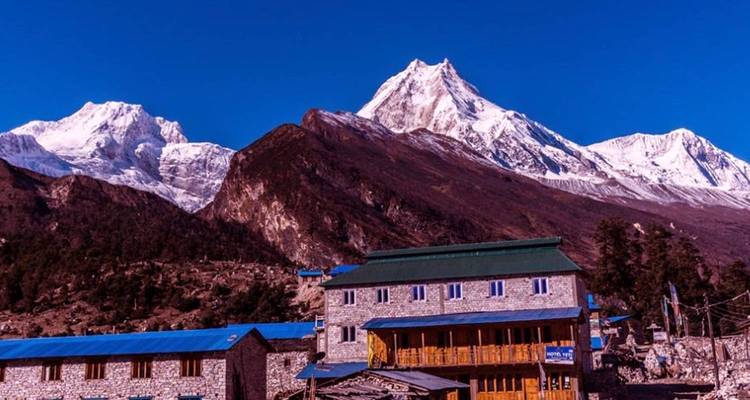 Entfernte Bergkette mit Gebäuden im Vordergrund, schneebedeckt.