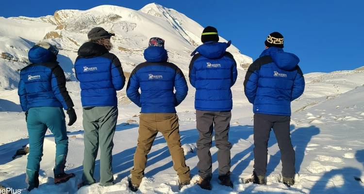 Gruppe von Menschen mit dem Rücken zugewandt, die passende Jacken in verschneiten Bergen tragen.