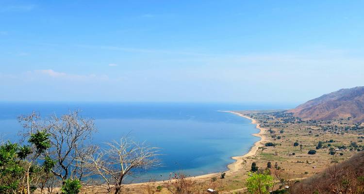 Ein Panoramablick auf einen großen See, der von Hügeln und Bäumen umgeben ist.
