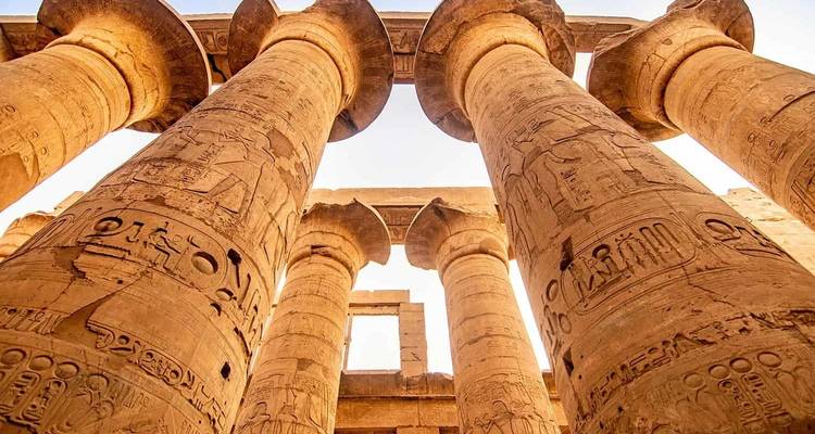 Grandes colonnes antiques avec des hiéroglyphes contre un ciel dégagé.