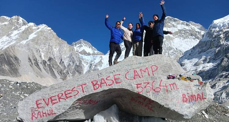 Gruppe steht auf Felsen mit Everest Base Camp Inschrift.