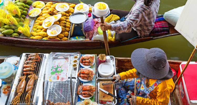 Marché flottant avec des vendeurs proposant divers produits dans des bateaux.