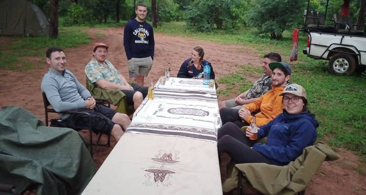 Groupe de personnes assises autour d'une table à l'extérieur.