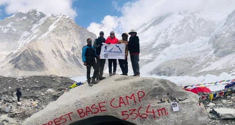 Groep mensen die staat bij Everest Base Camp met berg achtergrond.