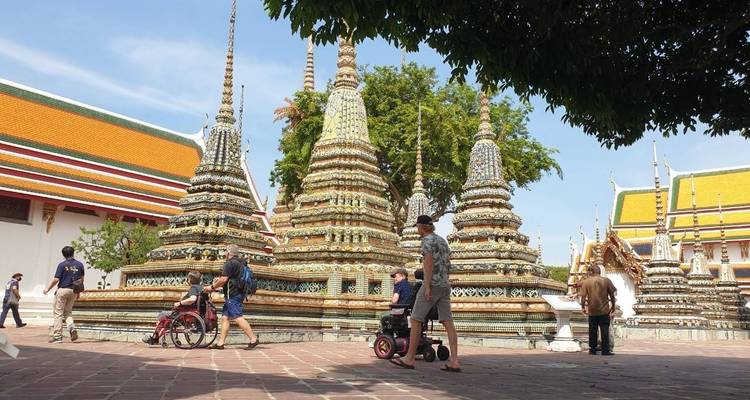 People exploring a temple complex with colorful stupa-like structures.