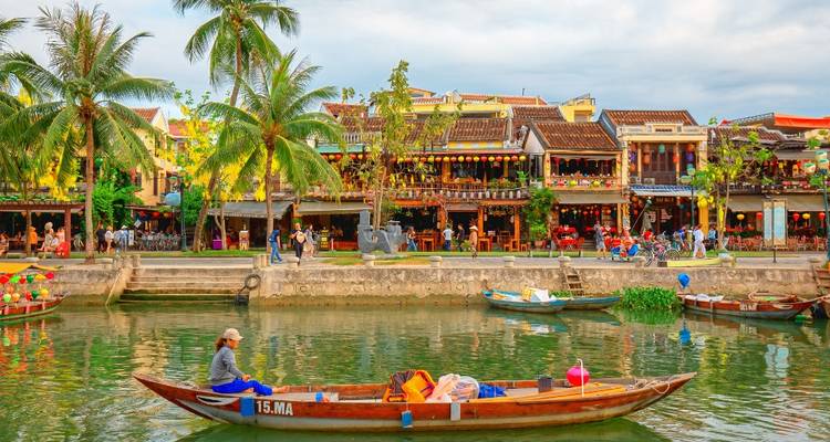 Kleurrijke gebouwen aan de rivier met een boot op de voorgrond.
