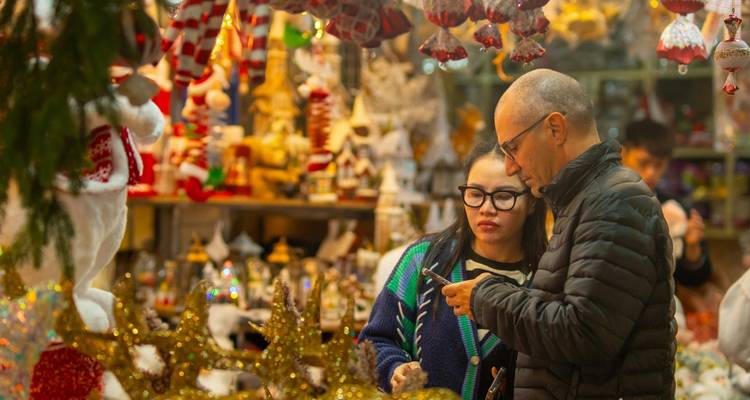 Mensen die door een levendige markt met kleurrijke decoraties wandelen.