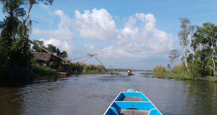 Boottocht door een waterweg met groen en blauwe lucht.