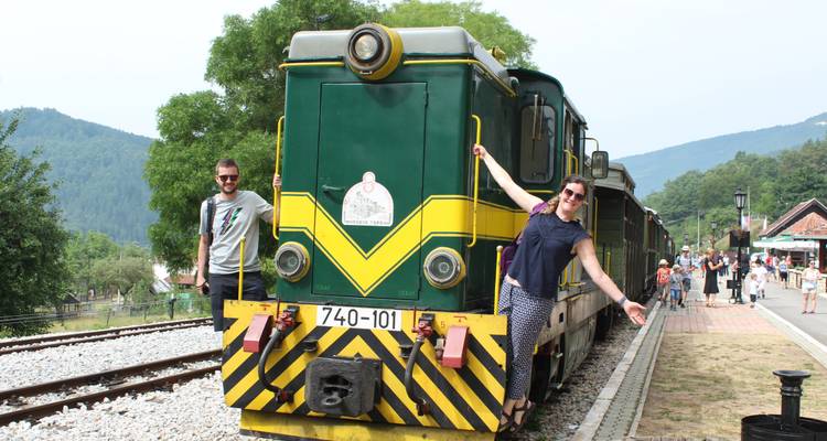 Personas posando con un tren vintage en un área escénica.