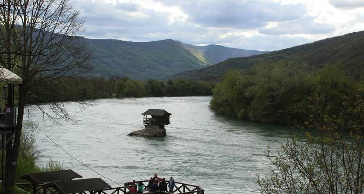 Casa pequeña sobre una roca en el medio de un río que fluye.