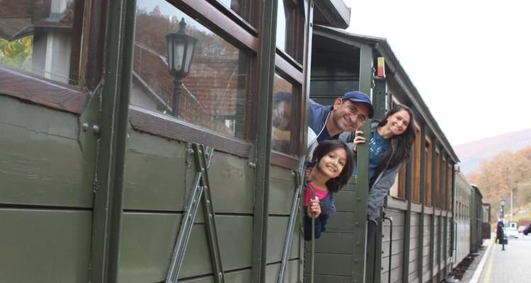 Familia feliz asomándose de un vagón de tren histórico.