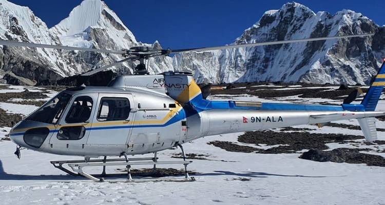 Hélicoptère sur un sol enneigé avec des montagnes en arrière-plan.