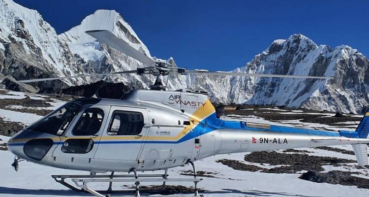 Un hélicoptère sur un terrain enneigé avec des montagnes alentour.
