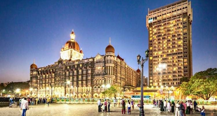 Das Taj Hotel und das Gateway of India beleuchtet in der Abenddämmerung.