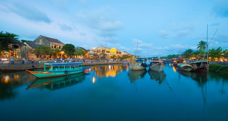 Bewegingsonscherpe opname van kleurrijke boten op een rivier in de schemering.