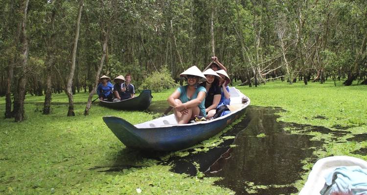 Group of people in boats navigating through a flooded forest area.