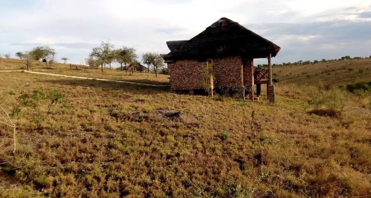 Ein rustikales hüttenartiges Gebäude in einer weitläufigen, trockenen Landschaft.