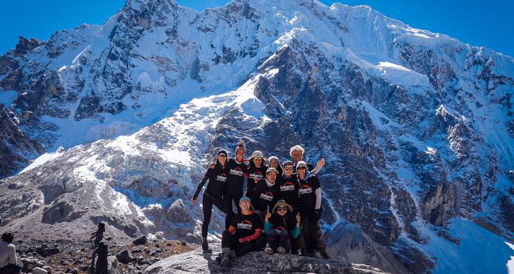 Groupe de randonneurs posant avec une montagne enneigée en arrière-plan.