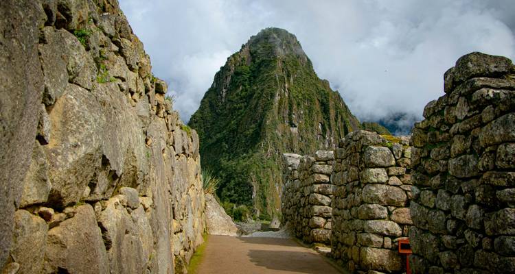 Sentier aux murs de pierre avec les paysages du Machu Picchu qui émergent au-delà.