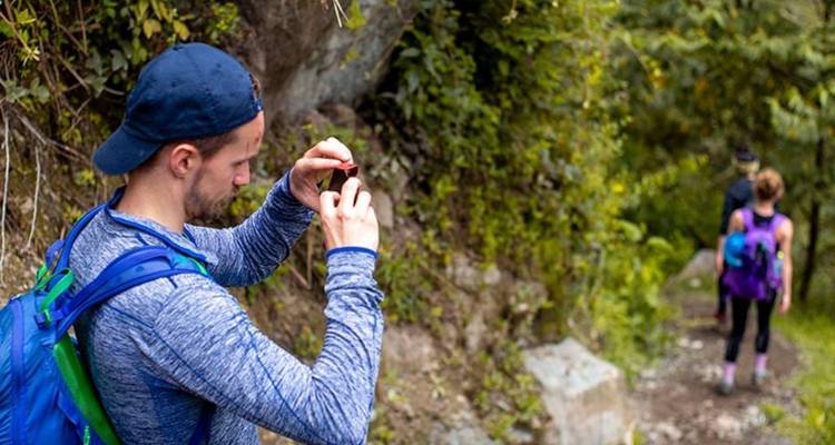 Persona tomando una foto en un sendero de senderismo con otros en el fondo.