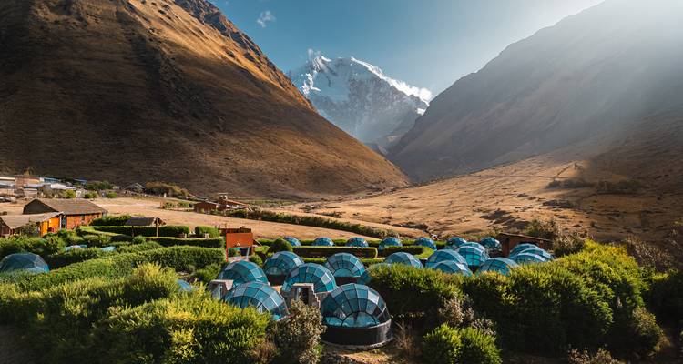 Alojamientos de iglú de cristal enclavados en un valle con montañas imponentes.