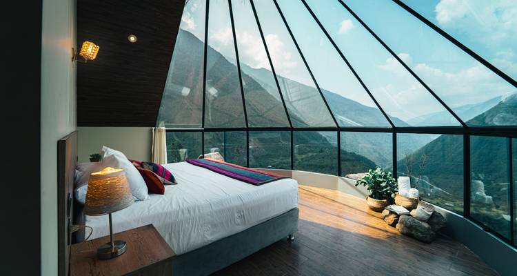 Alojamiento lujoso con paredes de cristal y vistas a la montaña.