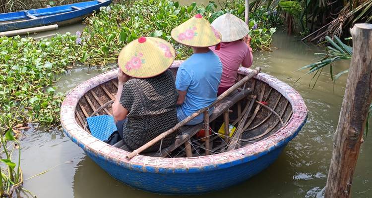 People in a round boat wearing traditional hats on a river.