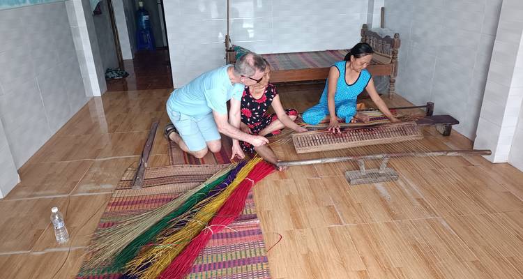 People weaving on a loom indoors.
